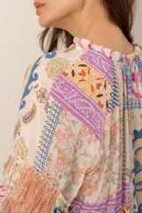 Blusa de manga larga con diseño patchwork multicolor que combina estampados florales, paisley y geométricos, con escote en V y mangas abullonadas.