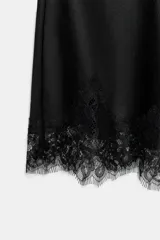 Shorts de tiro alto confeccionados en tejido satinado color crema, con cintura elástica y detalle de encaje negro a contraste en el bajo.