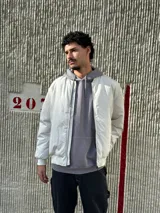 Buzo canguro gris con capucha y cordón ajustable, bolsillo tipo canguro y puños y cintura acanalados.