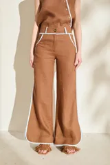 Pantalón azul marino de corte wide leg con detalles en tono marrón tostado en la cintura, bolsillos y bordes laterales, cuenta con trabillas para cinturón y cierre frontal.