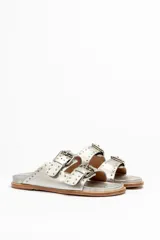 Sandalias de cuero color negro con dos tiras anchas sobre el empeine, cada una con hebillas metálicas ajustables y detalles de tachas plateadas. La suela es de cuero con un borde de color madera.