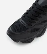 Championes estilo dad sneaker de diseño robusto, color negro, con suela alta y recortes laterales. Presentan cierre mediante cordones y una estructura que combina paneles de malla y material sintético.