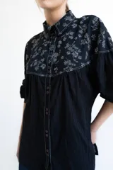 Camisa negra de manga larga con canesú estampado con diseño floral, cuello camisero y cierre frontal con botones.