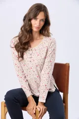 Remera de manga larga color beige con estampado floral en tonos rosados y verdes. Tiene cuello redondo y botones frontales.