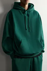 Sudadera con capucha de corte relajado, confeccionada en tejido de algodón con interior cepillado. Presenta manga larga, bolsillo frontal tipo canguro y acabados en rib en puños y bajo.