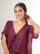 Vestido midi de seda italiana color bordó, con escote en V, sobrecapa fruncida y diseño fluido. Cuenta con mangas cortas amplias y elástico en la cintura.