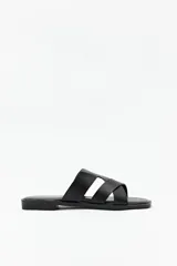 Sandalias planas negras con tiras anchas cruzadas, punta cuadrada y base levemente acolchonada.