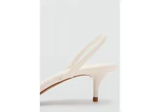Sandalias de tacón fino bajo tipo kitten heel, color marfil, con tira delantera fina y tira ajustable en el talón.