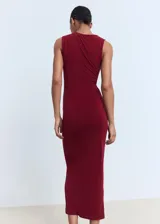 Vestido midi entallado color bordó, sin mangas, con cuello redondo y detalle drapeado en el lateral. Presenta un aplique de joya decorativa en el tirante.