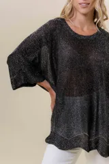 Buzo de tejido liviano con brillo sutil tipo lurex, color beige o dorado claro. Presenta un calce suelto (oversize) con mangas amplias y cuello redondo. El ruedo tiene un detalle de terminación festoneado con pequeños calados.