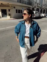 Camisa de jean celeste, de corte holgado, con cuello camisero, cierre frontal con botones y bolsillo de parche en el pecho.