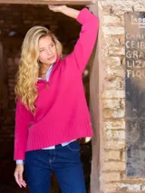 Buzo de lana 100% Lambswool color fucsia, con cuello alto y medio cierre frontal.