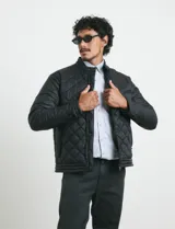 Campera capitoneada de color azul oscuro, con cierre frontal de metal y botones a presión. Presenta bolsillos laterales y en el pecho con cierres metálicos.