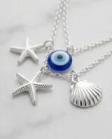 Collar triple de plata 925 con dijes colgantes que incluyen un ojo turco, caracoles de mar, estrellas de mar y una circonia central.
