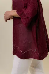 Buzo de tejido liviano con brillo sutil tipo lurex, color beige o dorado claro. Presenta un calce suelto (oversize) con mangas amplias y cuello redondo. El ruedo tiene un detalle de terminación festoneado con pequeños calados.