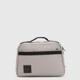 Bolso tipo maletín color gris claro con detalles en negro, cuenta con asa superior, cierre principal, bolsillo frontal con cierre y parche con logo en la parte inferior.