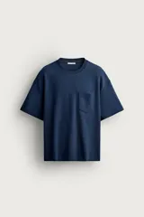 Camiseta azul marino de corte relajado, confeccionada con mezcla de algodón. Cuenta con cuello redondo, mangas cortas y un bolsillo aplicado en el pecho.