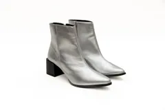 Botas cortas plateadas de cuero con punta fina y cierre lateral. Taco geométrico color negro.