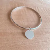 Pulsera rígida de plata 925 con dije redondo grabado.