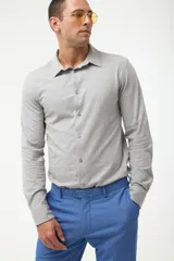 Camisa gris de piqué con cuello clásico, manga larga y cierre frontal con botones.