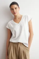 Remera blanca de manga corta, con cuello en V decorado con detalles de vainillas.