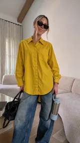 Camisa oversize color mostaza, de manga larga con puños abotonados, cuello clásico y bolsillo aplicado en el pecho.