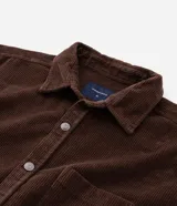 Camisa de terciopelo cotelé color negro, de corte clásico con cuello solapa, manga larga, cierre frontal de botones y un bolsillo aplicado en el pecho.