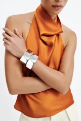 Top de cuello halter satinado en color naranja tostado, con espalda descubierta y cierre trasero de botones.
