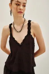 Top negro con escote en V y tirantes finos, ambos con detalles de encaje. Presenta un diseño de cadenas bordadas con cuentas en la parte frontal.