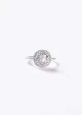 Anillo de plata 925 con diseño de roseta, con una piedra central redonda de zirconia blanca rodeada por un pavé de zirconias más pequeñas y banda fina con detalles texturados.