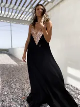 Vestido largo de fiesta color negro, con corte holgado y escote en V profundo decorado con lentejuelas doradas.
