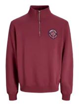 Buzo de manga larga color rojo tibetano, con cuello alto y cierre frontal. Presenta un fit suelto, interior afelpado y una estampa circular en el pecho con el texto "Originals Studio 1990".