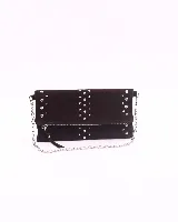 Bandolera de cuero gamuzado color marrón oscuro, con diseño rectangular y solapa frontal decorada con tachas metálicas plateadas. Incluye una cadena metálica plateada larga para usar al hombro o cruzada, y una cadena más corta para llevar como sobre.