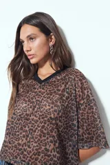 Remera de manga corta con silueta relajada y caída fluida. Presenta un diseño con estampado animal print y escote en V con terminación en contraste.
