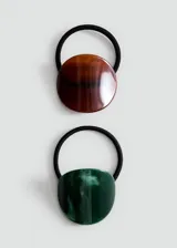 Pack de dos gomas de pelo elásticas con apliques decorativos de resina y acetato, uno circular en tonos marrones y otro ovalado en tonos verdes.