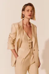 Blazer color beige de corte clásico, con solapas de muesca, cierre frontal con un botón dorado y bolsillos delanteros con solapa.