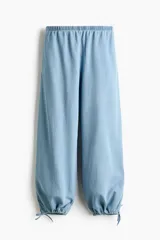 Pantalón de denim suave en color celeste, con cintura elástica fruncida y diseño de corte holgado con piernas estilo globo. Cuenta con detalles de cordones ajustables en los bajos.
