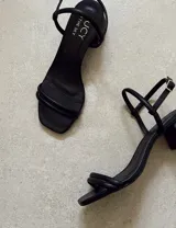 Sandalias de tacón bajo color blanco, con tiras finas y cierre con hebilla.