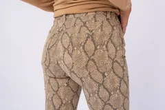 Pantalón de jean ajustado con estampado de piel de serpiente en tonos marrones.