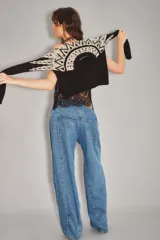 Jean de corte wide leg en color azul medio, con costuras verticales decorativas a lo largo de las piernas y diseño de tiro medio.