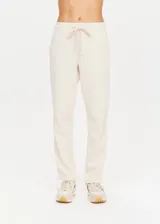 Pantalón deportivo color crema de corte recto con cintura elástica, cordón de ajuste y cinta de rayas plateadas en los laterales.