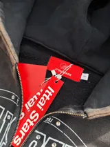 Campera canguro con cierre frontal, capucha y bolsillos tipo canguro, en tono marrón con efecto gastado vintage y estampa gráfica blanca con detalles de strass en el pecho.