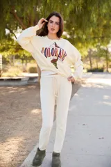 Sweater color crema con cuello redondo y estampado gráfico de montañas y la palabra "COLORADO" en el frente.