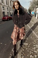 Chaqueta estilo bomber de corte oversize en color marrón oscuro, confeccionada con acabado aterciopelado. Presenta un cuello de solapa con detalle de pelo sintético desmontable, cierre frontal oculto con cremallera y botones a presión, bolsillos delanteros con solapa y bajo elástico.