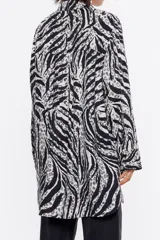 Camisa larga de viscosa con estampado de cebra en blanco y negro. Modelo de corte recto, cuello camisero, manga larga, puño con botones y cierre frontal de botonadura.