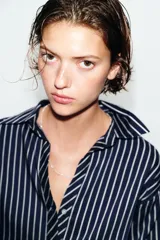 Camisa de corte oversize con estampado de rayas verticales, cuello solapa, escote en pico y mangas abullonadas con puños anchos. Cierre frontal mediante botones.