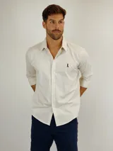 Camisa de manga larga en color beige, confeccionada en tejido de lino con cuello clásico y cierre frontal de botones. Presenta un pequeño logo bordado en el pecho.