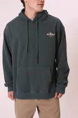 Buzo con capucha color verde oscuro, de corte holgado, con bolsillo frontal tipo canguro y cordones ajustables en el cuello. Presenta un pequeño bordado o estampado en el pecho con forma de flor y la frase 'get Ahead'.