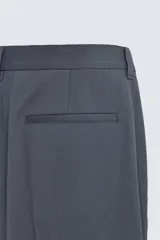 Pantalón de traje con corte flare fit, confeccionado en tejido con lana. Presenta diseño de tiro medio con pinzas frontales, bolsillos laterales y bolsillos traseros de vivo. Cierre frontal con cremallera y botón.