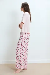 Pijama compuesto por una remera de manga corta en color rosa claro con un pequeño bordado de labios en el pecho y un pantalón largo estampado con motivos de labios en tonos rojos y rosas.